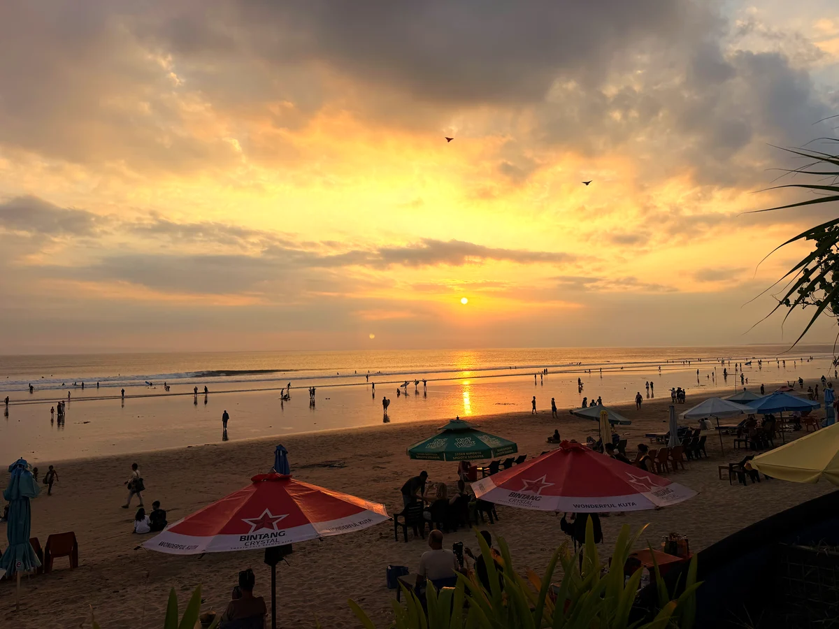 Sonnenuntergang über dem Strand von Kuta, im Vordergrund Sonnenschirme