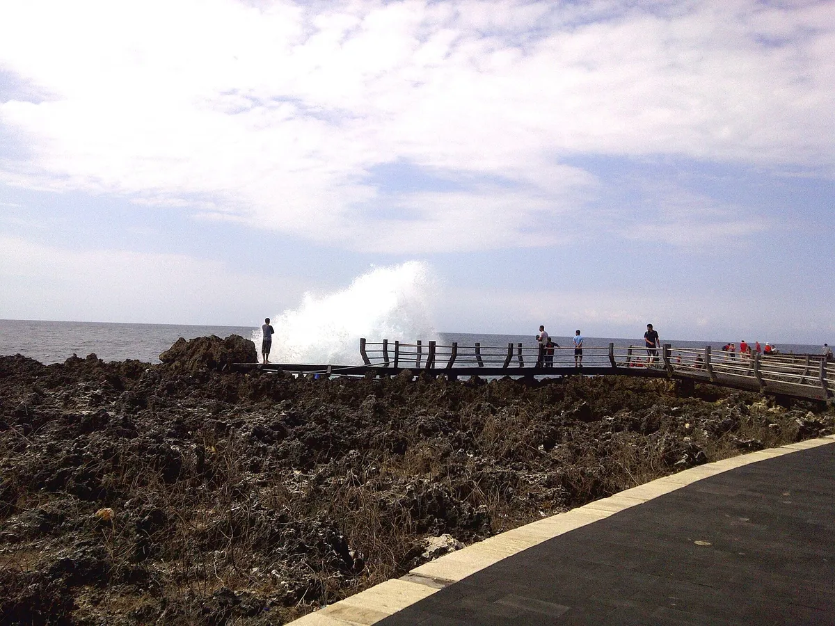 Welle spritzt an der Küste bei Nusa Dua an den Klippen hoch, Aussichtsweg am Rand