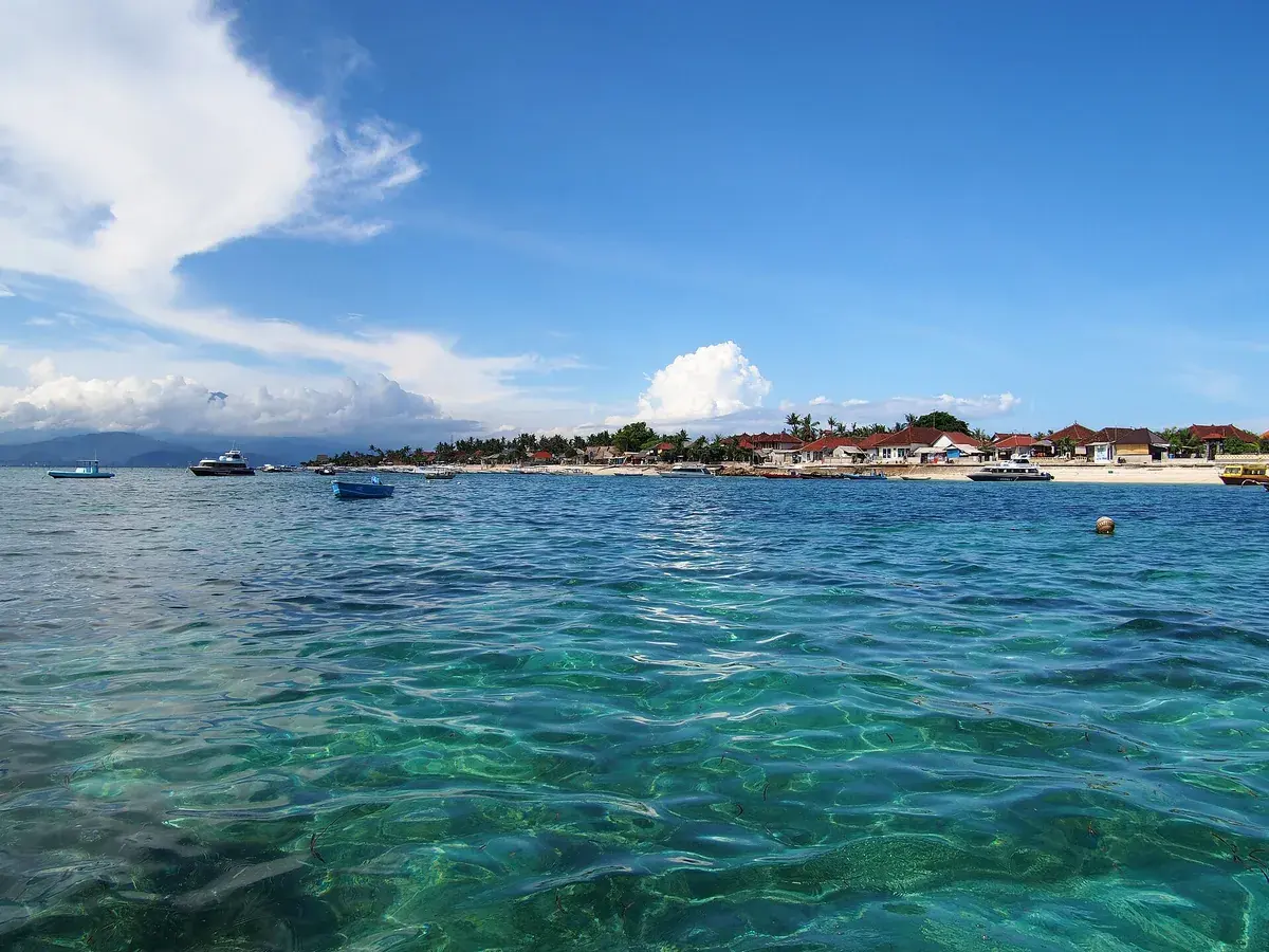 Klares türkises Wasser vor Nusa Lembongan, am Ufer Häuser und Boote