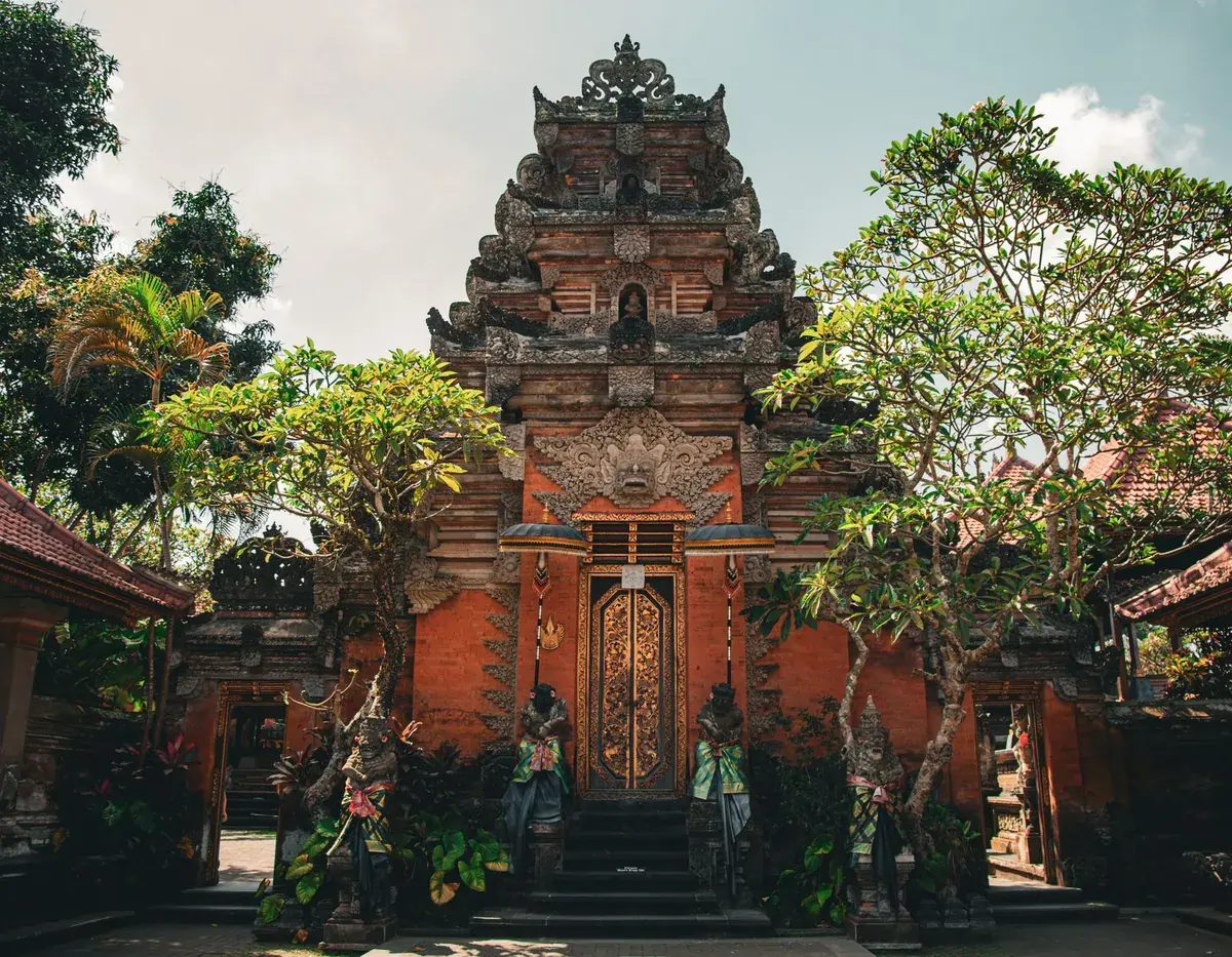 Tor des Ubud Palace mit Steinfiguren und Palmen