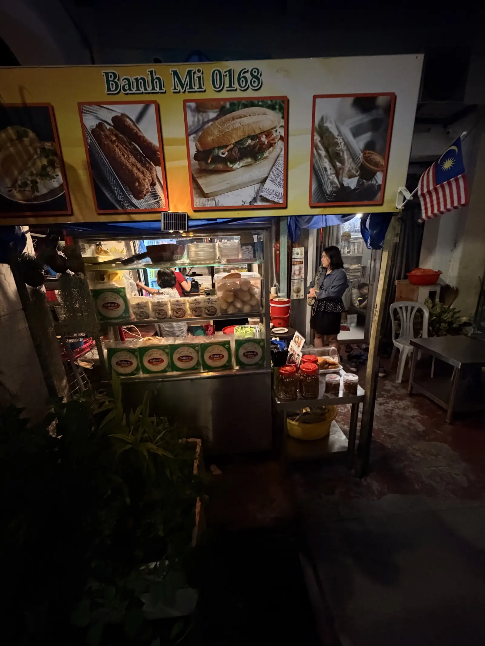 Der beleuchtete Stand von Penang Banh Mi 168 am Abend