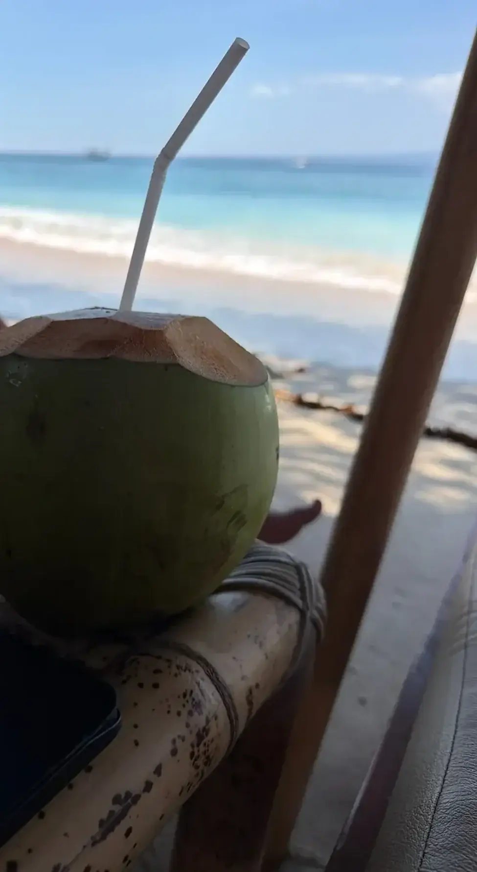 Frische Kokosnuss mit Strohhalm am Strand