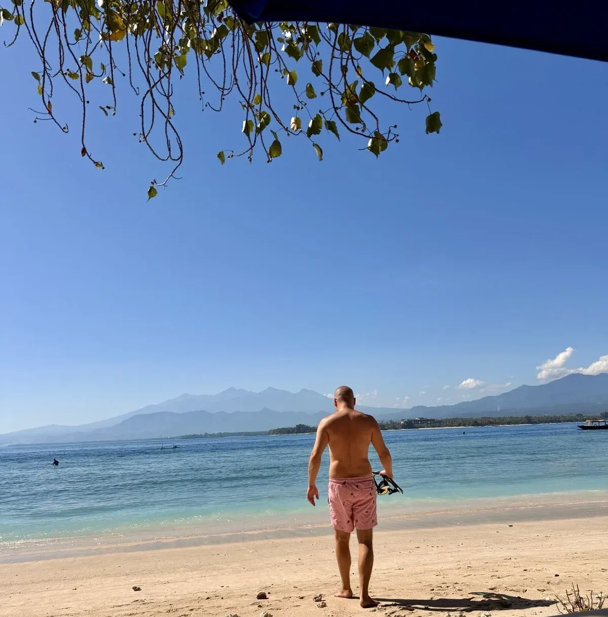 Marc geht am Strand von Gili Air mit Schnorchelausrüstung ins Wasser