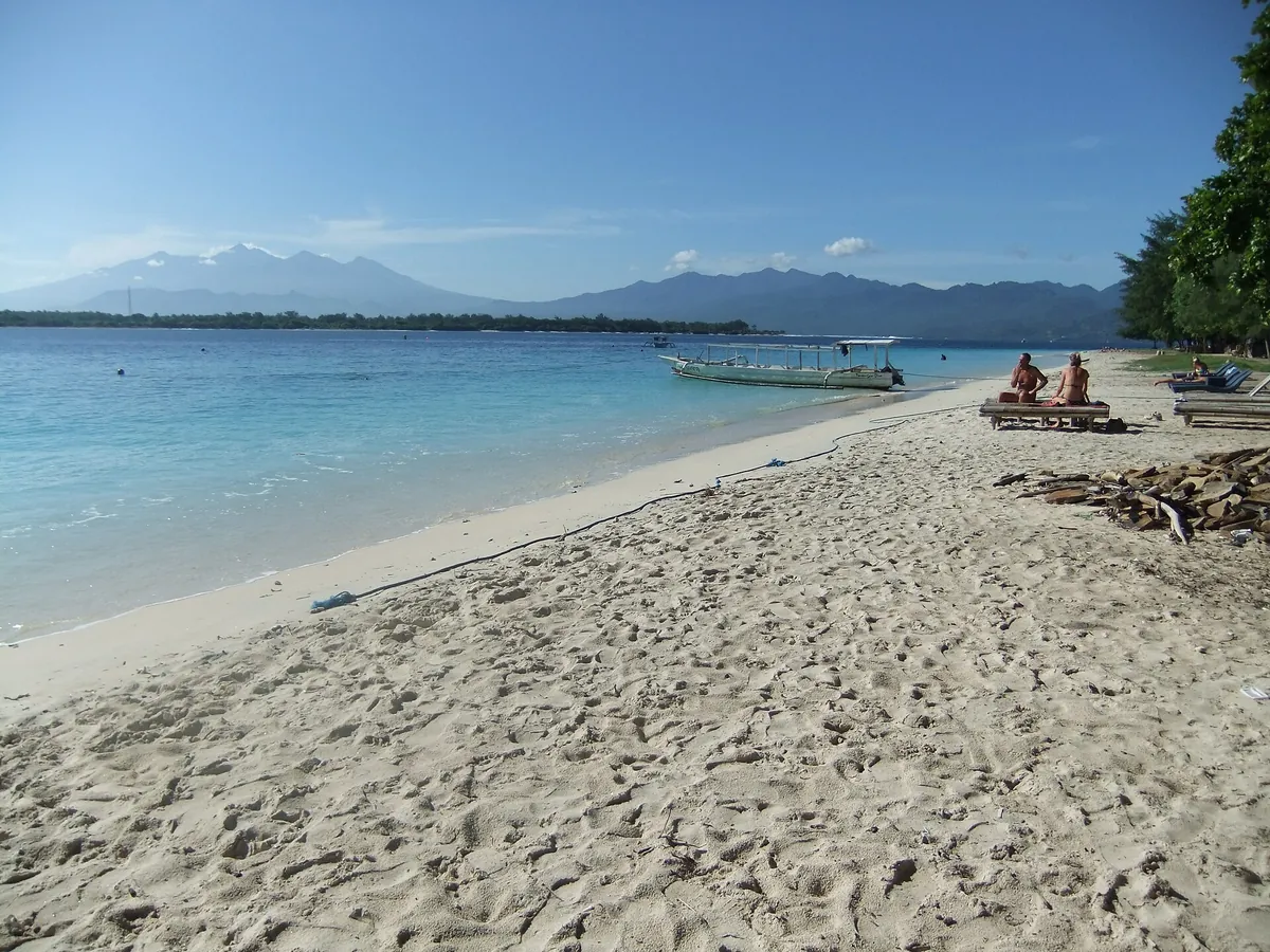 Heller Sandstrand auf Gili Trawangan mit Booten und Lombok im Hintergrund