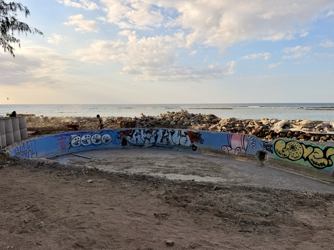 Baustelle und verlassener, mit Graffiti besprühter Pool am Strand von Gili Air