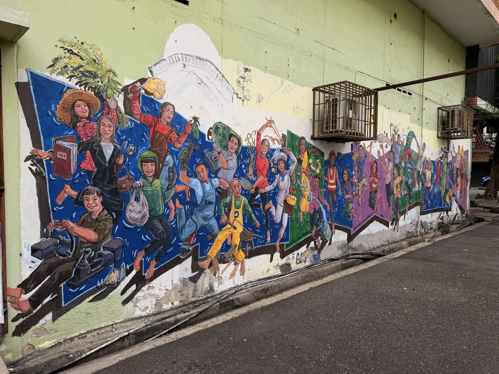 Eine lange Wand mit vielen bunten Wandbildern nebeneinander
