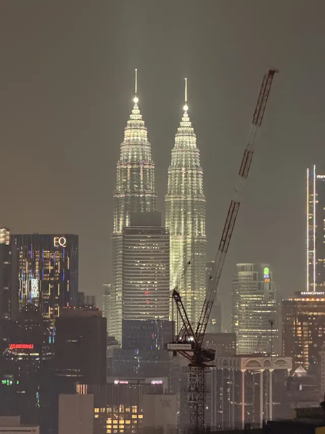 Blick vom Dach auf die beleuchteten Petronas Towers in Kuala Lumpur