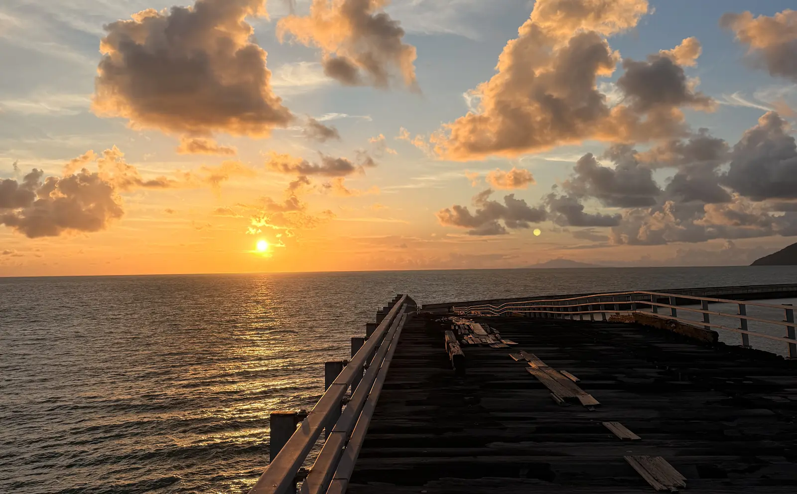 Sonnenuntergang über dem Meer, im Vordergrund ein alter Holzsteg auf Langkawi