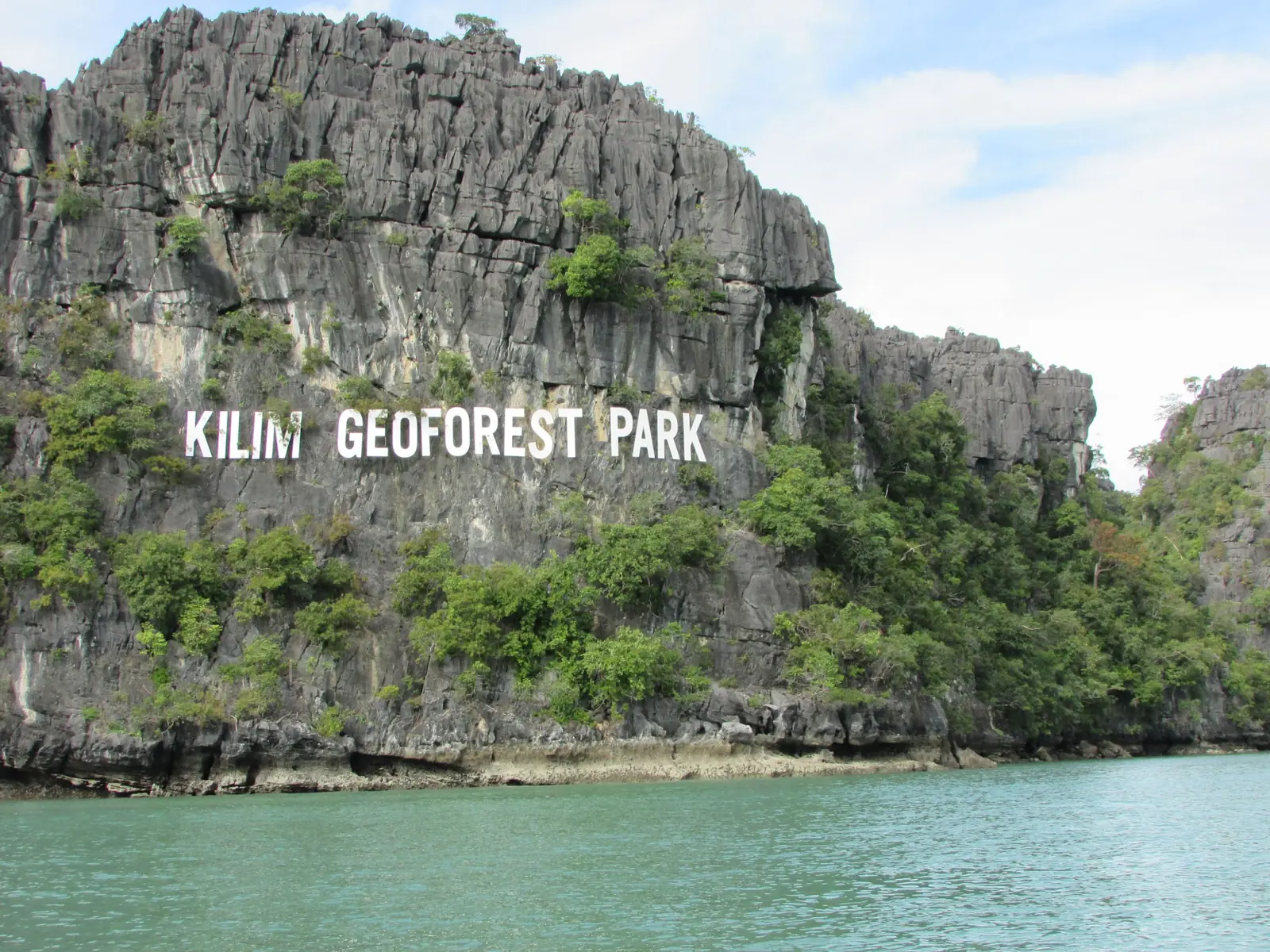 Kalkfelsen mit dem Schriftzug Kilim Geoforest Park über dem Wasser
