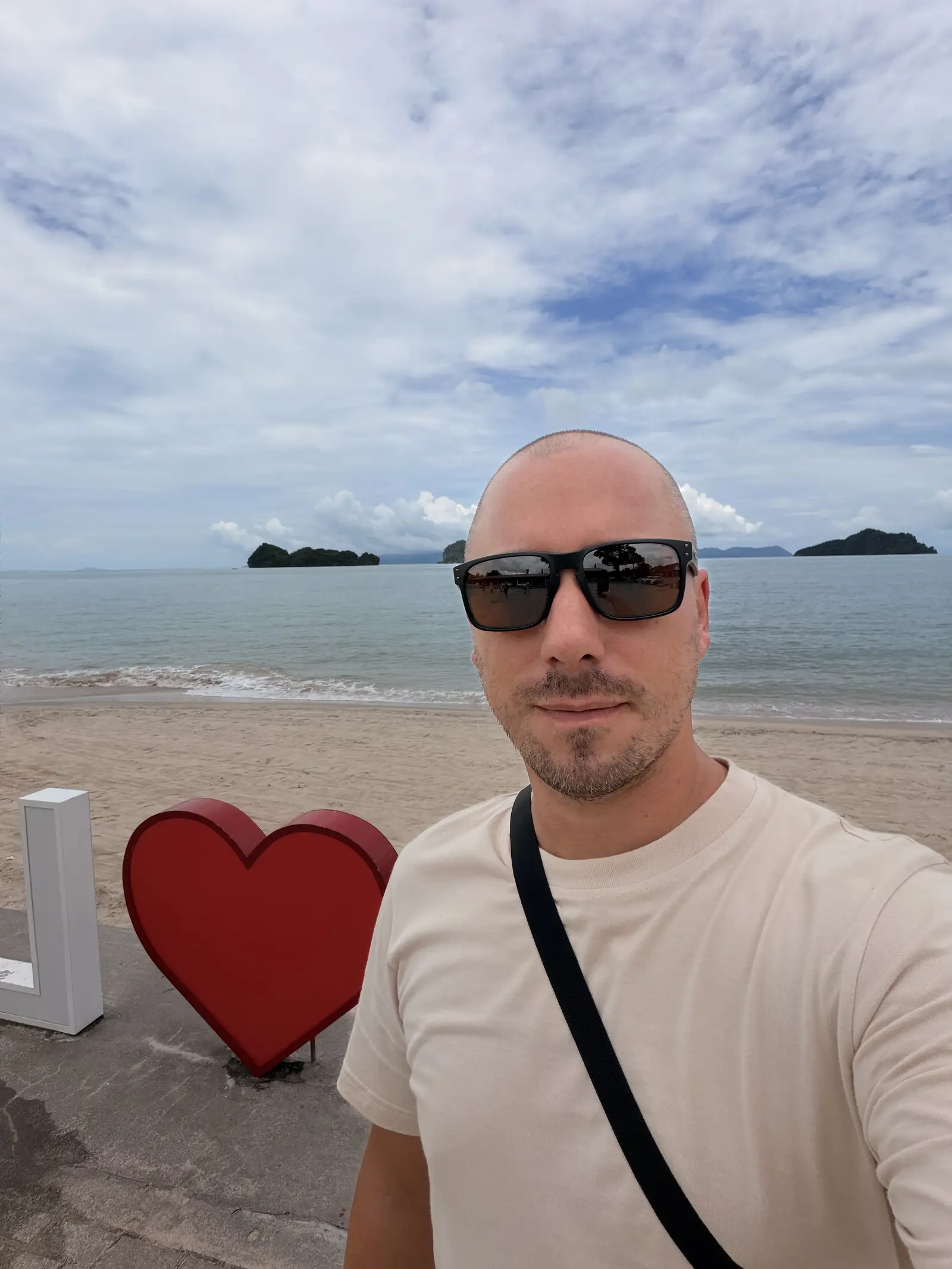 Marc mit Sonnenbrille neben einem roten Herz am Strand von Tanjung Rhu