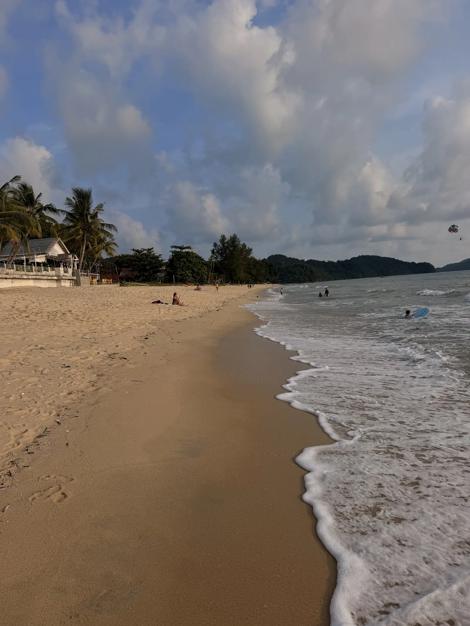 Breiter Sandstrand von Pantai Cenang mit sanften Wellen