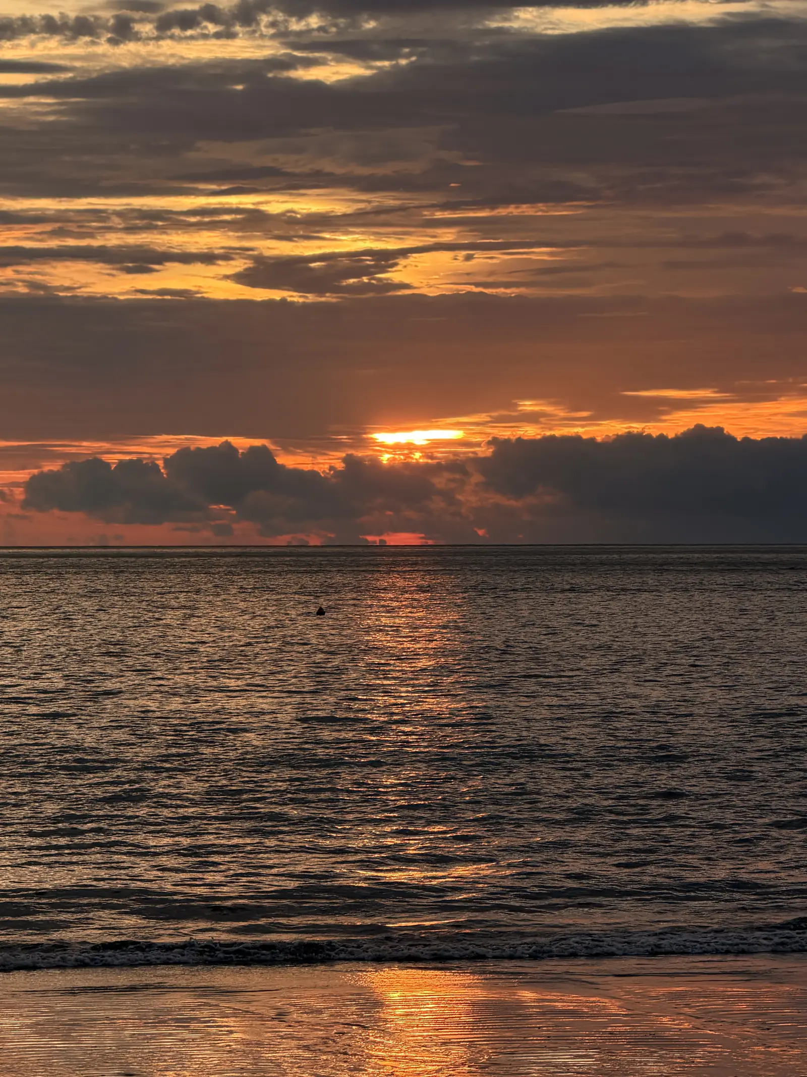 Roter Sonnenuntergang über dem Meer mit Wolkenband
