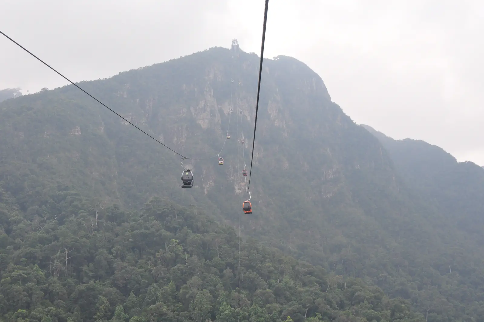 Gondeln der Seilbahn vor dem Gunung Mat Cincang im Nebel