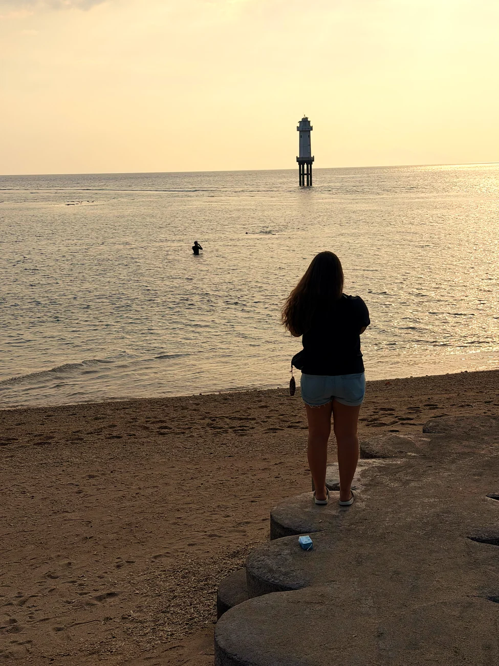 Fabienne steht am Abend am Strand von Senggigi und schaut aufs Meer