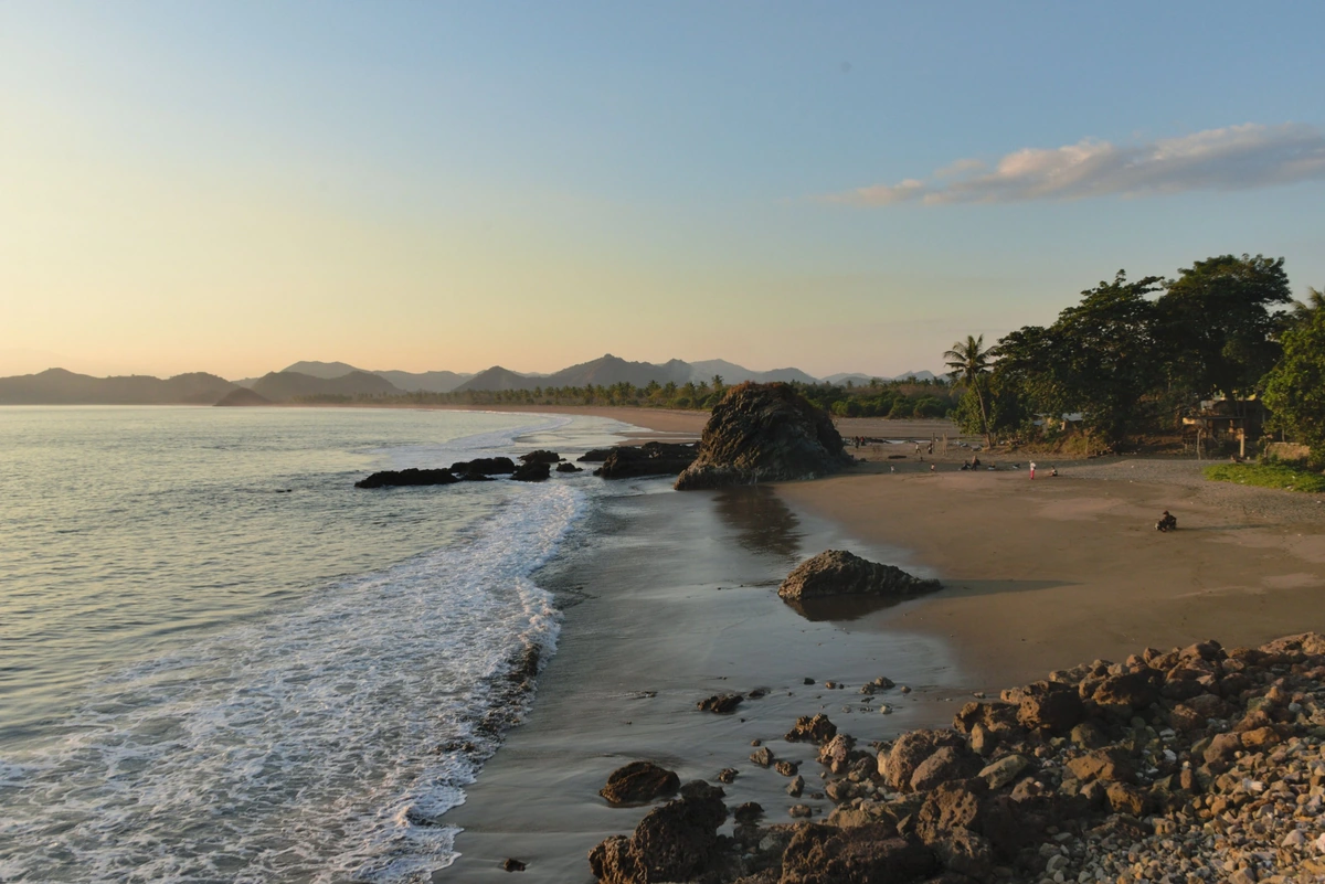 Abendlicht an einem Strand mit Wellen und Felsen auf Lombok