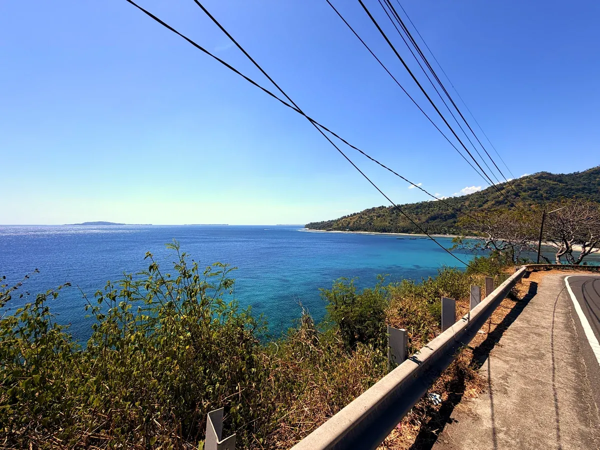 Küstenstrasse mit Blick auf eine Bucht und ein Stromkabel