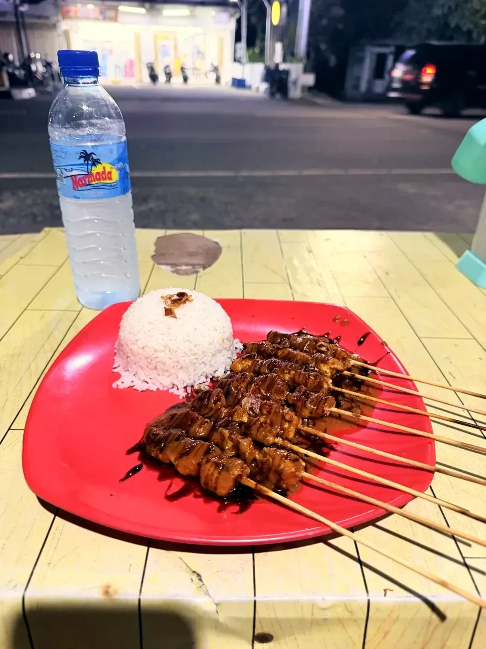 Satay-Spiesse mit Reis auf rotem Teller
