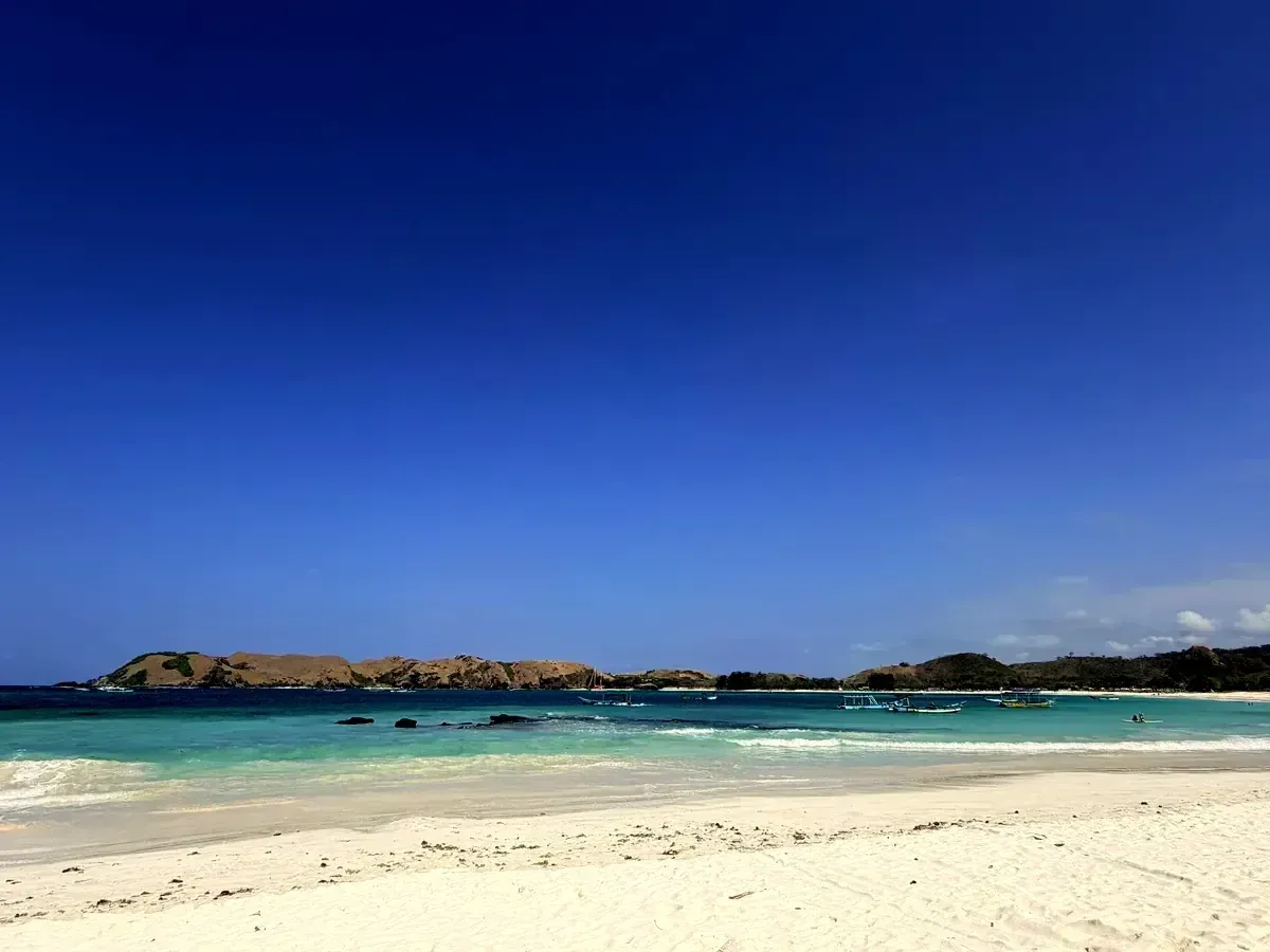 Weisser Sandstrand mit einer kleinen Insel im Hintergrund