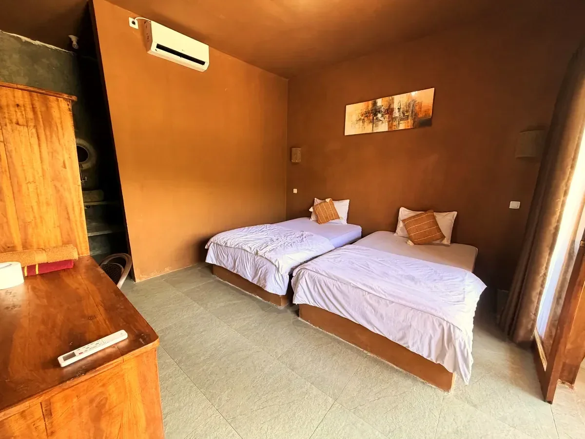 Zimmer im Fullmoon Homestay in Kuta mit zwei Betten und Holzmöbeln