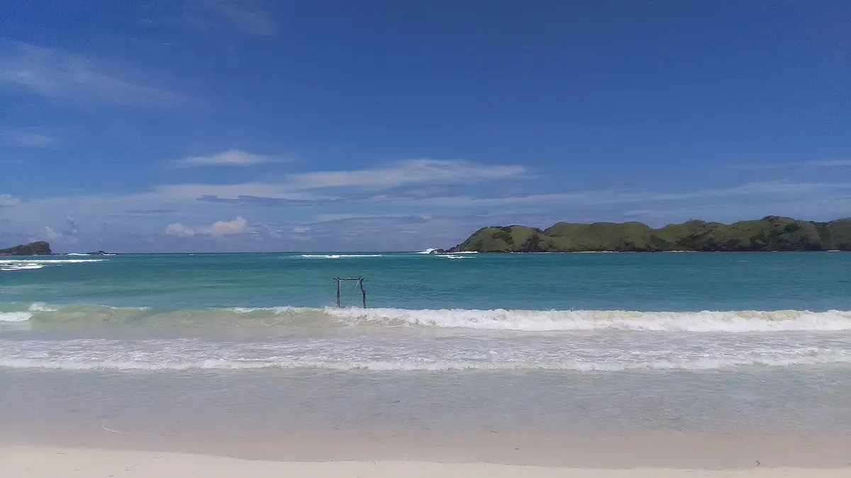 Strand von Tanjung Aan mit türkisem Wasser und Insel am Horizont