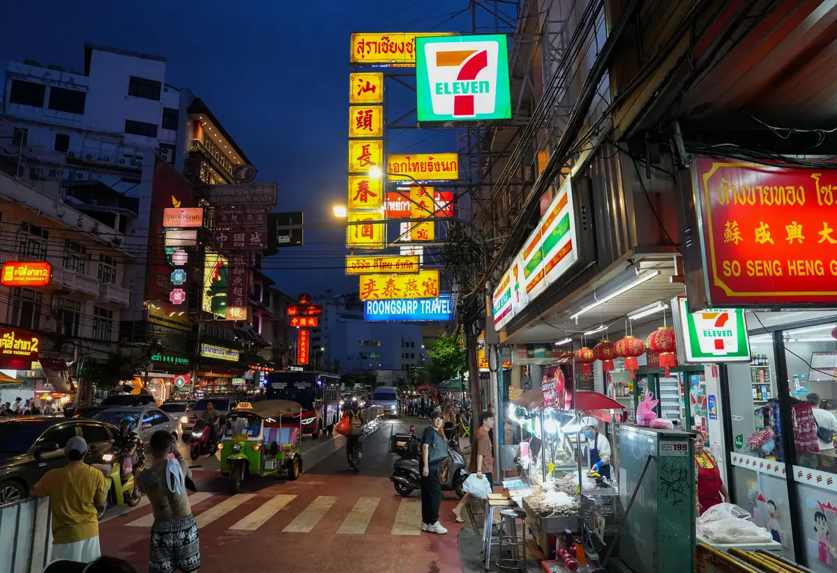 Abendliche Strasse in Bangkok mit 7-Eleven und Tuk-Tuk