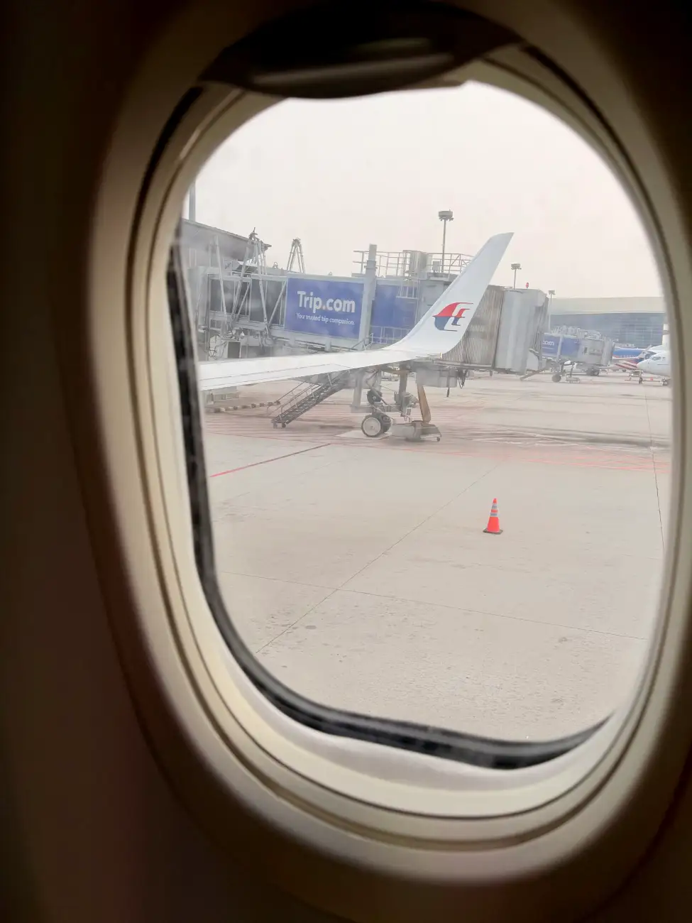 Blick aus dem Flugzeugfenster auf Flügel und Fluggastbrücke